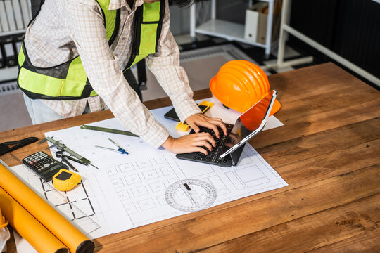 Female architect engineer is drafting blueprints using CAD software, focusing on sustainable infrastructure, renewable energy solutions, and adhering to building codes