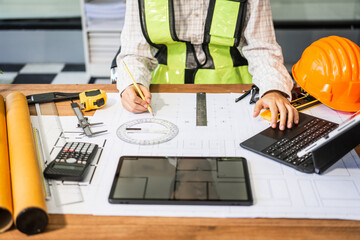 Female architect engineer is drafting blueprints using CAD software, focusing on sustainable...