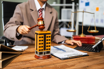 A young businesswoman is working at her desk, managing lease agreements and coordinating with the HOA for an apartment complex, focusing on tenant relations and property maintenance.