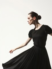 Fototapeta premium Timeless Elegance - Fashion model in a classic black dress against white background with copy space.