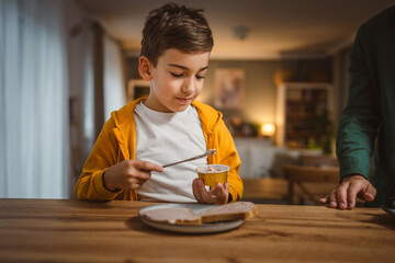 Portrait of young boy sit at kitchen and smear pate prepare breakfast