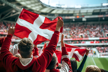 Fans waving the flag of Denmark at a football match, with the stadium crowd in the background