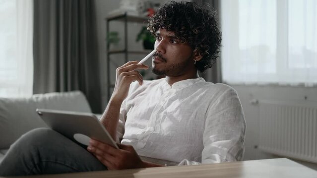 Portrait of handsome creative young man student digital illustrator thinks questioningly create idea for new drawing at desk next to tablet at home workplace
