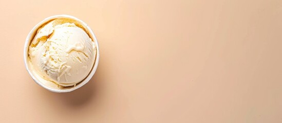 Top view of vanilla flavored ice cream in a paper tub on a light beige background