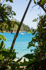 Paradisiacal view of the turquoise sea on an isolated island. Sailboat anchored at Praia do Dentista, Angra dos Reis, RJ, Brazil.