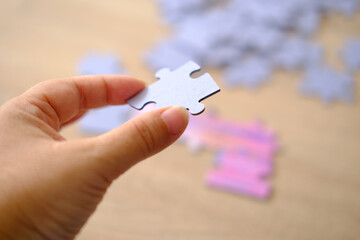 female hand holds cardboard puzzle piece, logical skills, puzzle solving and memory improvement,...
