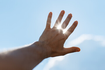 The man raised his hand to the sun and the rays of the sun shine through his fingers. Freedom, concept