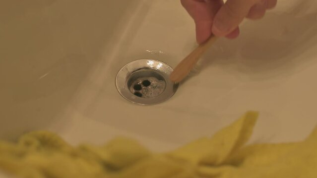 Cepillando a mano el desag&uuml;e de la bacha del ba&ntilde;o