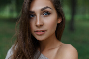 beautiful young woman with a clean face in a park in nature looks at the camera