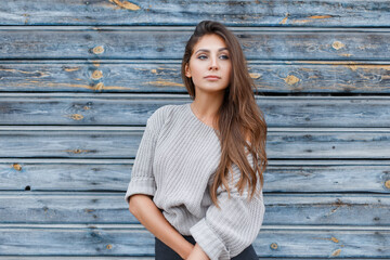 Obraz premium Fashion beautiful tender girl in a knitted sweater near a blue vintage wooden wall