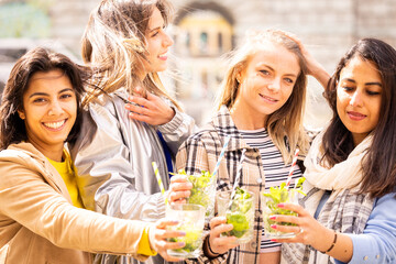 A group of four friends are happily laughing while enjoying drinks outdoors in a relaxed and joyful setting