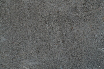 The surface of a plastered gray wall with a fine fraction of sand with all the irregularities and...