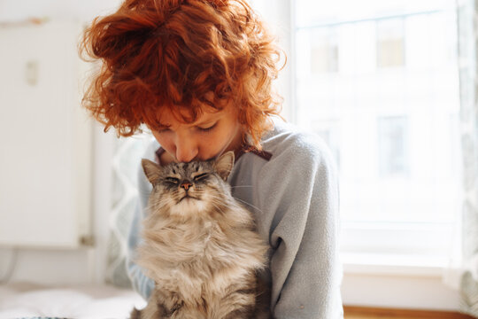 Portrait red-haired curly young woman with beloved fluffy domestic cat