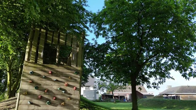 Wooden Climbing Wall With Colorful Holds in Backyard on Sunny Day