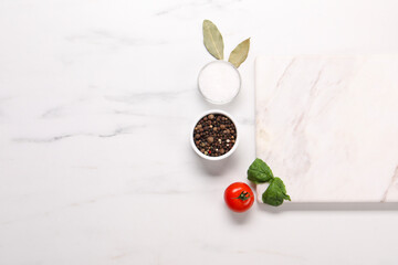 Cutting board, spices and tomato on white marble table, flat lay. Space for text