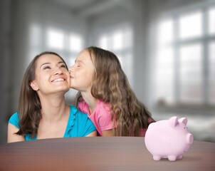 Cute little child with mother and piggy bank