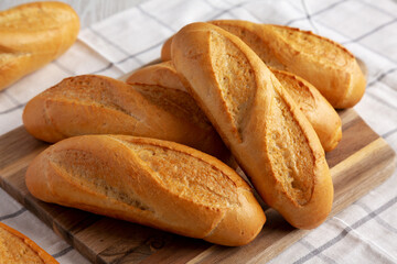 Homemade Mini baguettes on a wooden board, side view.