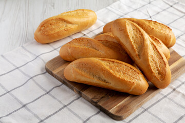 Homemade Mini baguettes on a wooden board, side view.