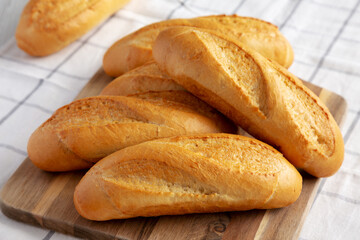Homemade Mini baguettes on a wooden board, side view. Close-up.