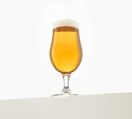 A full glass of amber beer with a frothy head, elegantly presented against a white background. The beer's rich golden hue and bubbles highlight its refreshing appeal, perfect for beverage advertising 