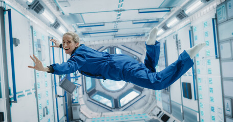 Portrait of a Courageous Caucasian Female Astronaut on Board a Spacecraft, Floating in Zero Gravity...