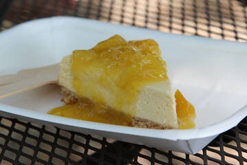 Lemon cheesecake with wooden fork in paper plate
