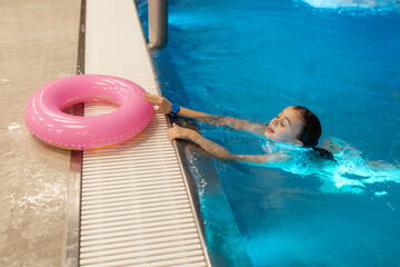 Closeup portrait of little swimmer girl take a rest after swimming in the swimming pool. Little...