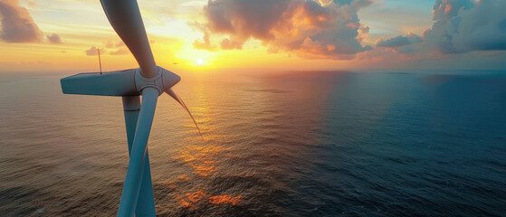 Aerial view of a wind turbine overlooking a serene ocean at sunset, capturing renewable energy and the beauty of nature.
