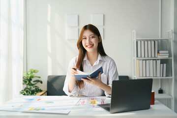 Student woman is sitting at a desk with a laptop and a notebook