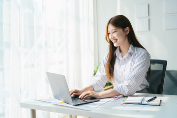 Fototapeta premium Student woman is sitting at a desk with a laptop and a notebook