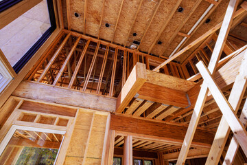 In new home under construction, trusses, post beams wood framework are being constructed out of unfinished house