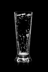 Empty beer glass with residue foam and bubbles, set against a black background. The remaining traces of beer create an intriguing visual contrast, perfect for beverage and bar-themed content.