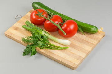 Various fresh vegetables and herbs on a wooden cutting board