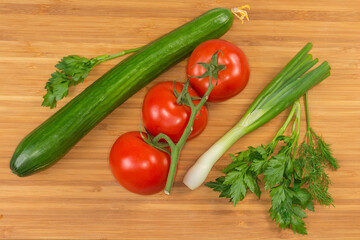 Various fresh vegetables and herbs on a wooden cutting board