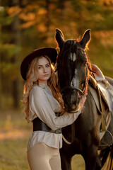 Obraz premium A young beautiful woman walks with her horse in the forest in early autumn. Walking with a horse in the forest.