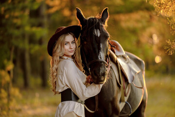 Obraz premium A young beautiful woman walks with her horse in the forest in early autumn. Walking with a horse in the forest.