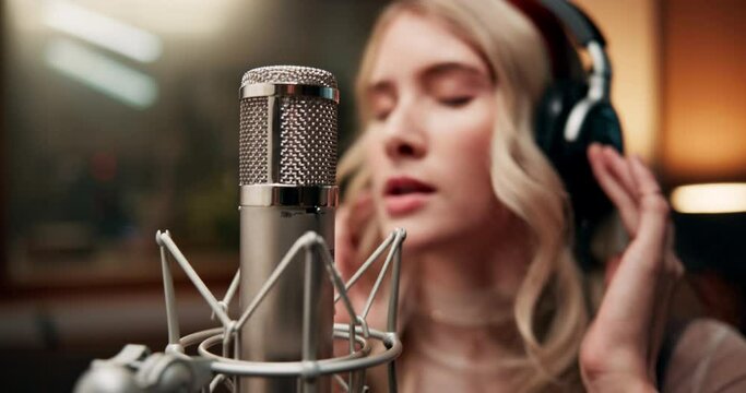 Girl, musician and singing in music studio for song recording with microphone for voice control. Female person, talent and passionate artist with headphone as singer for album and playlist and audio