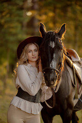 Obraz premium A young beautiful woman walks with her horse in the forest in early autumn. Walking with a horse in the forest.