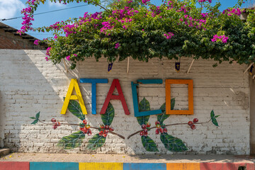 Sign Ataco made of colorful painted wooden planks on the brick fence in a small tourist town in...