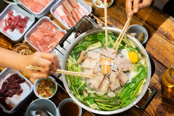 Hand holding chopsticks eating Thai barbecue Buffet party with friend.