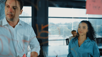 Skilled businessman presents marketing idea to project manager by using colorful sticky notes at...