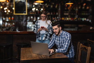 Two young people, husband and wife, Pub owners, working in their cafeteria, cleaning and calculating before opening time. Man and woman work in coffee shop, ordering drinks from delivery company