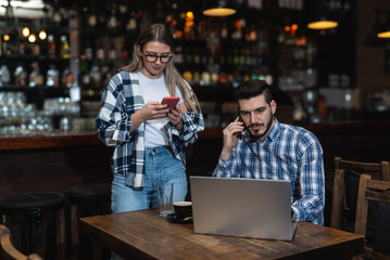 Two young people, husband and wife, Pub owners, working in their cafeteria, cleaning and calculating before opening time. Man and woman work in coffee shop, ordering drinks from delivery company