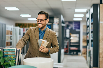 A smiling salesman holding some samples of ceramic tiles, ready to show to his customers.