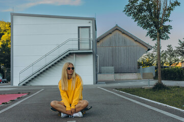 a young blonde girl in a yellow sweatshirt rides on the skateboard in the skate park