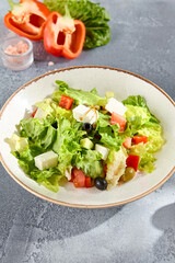 Greek salad with feta cheese and olives on a sunlit textured background