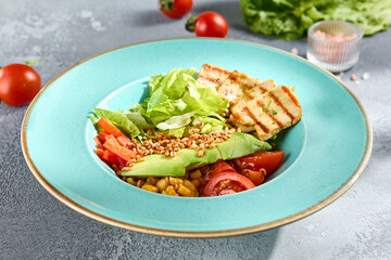 Grilled chicken fillet and avocado salad bowl with fresh veggies on a sun-kissed tabletop