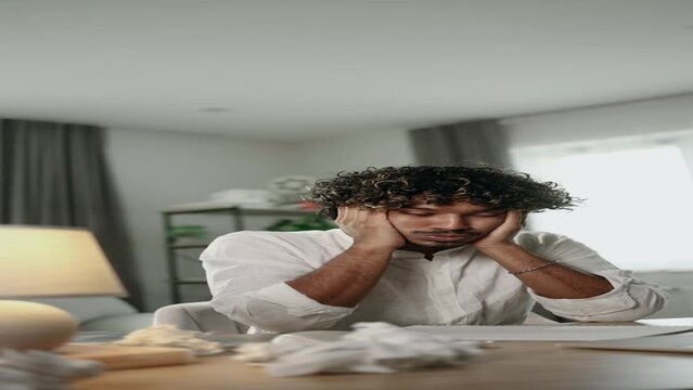 Vertical portrait of exhausted tired young indian man student or freelancer with failed ideas while take break at home workplace Tired male with creative block or lack of inspiration indoors	