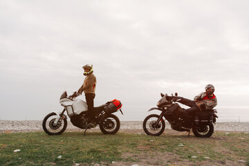 Fototapeta premium Bikers friends in motorcycle trip on adventure enduro motorcycles resting on sea shore