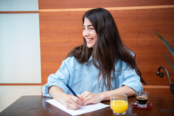 Young businesswoman sitting at desk at home smiling and looking away